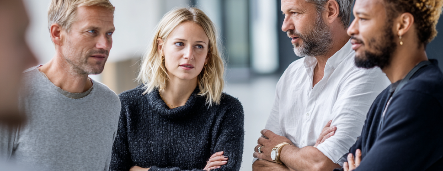 Verunsicherte Mitarbeiter stehen im Halbkreis und sprechen miteinander